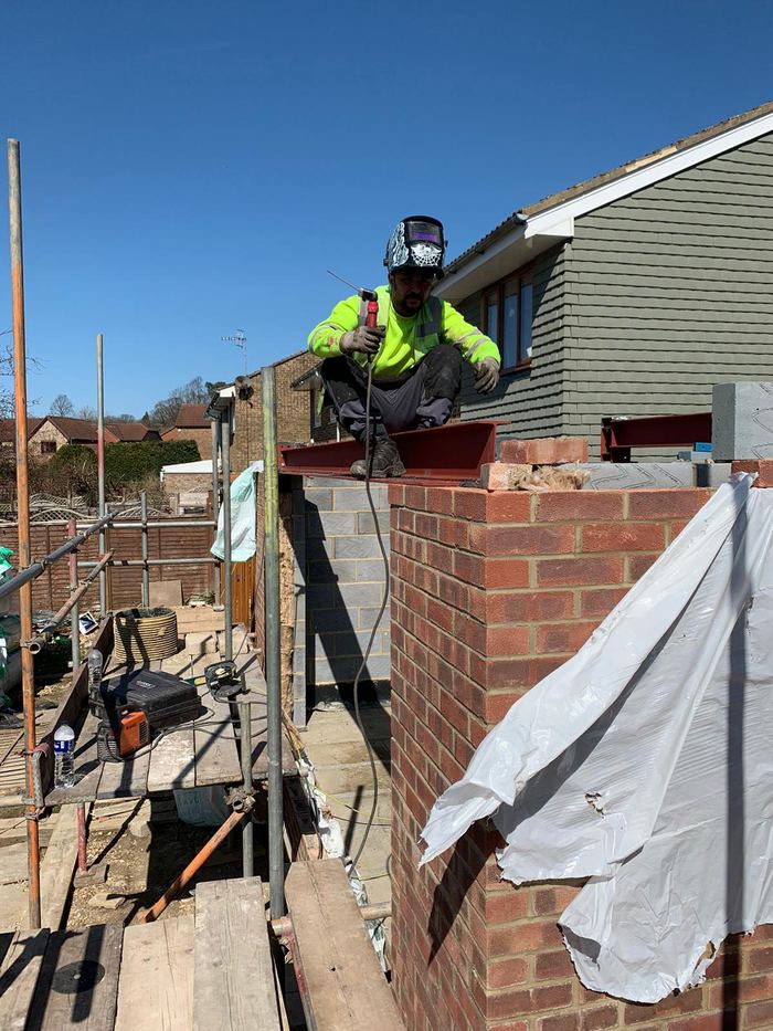Welder fitting a steel beam on a residential roof extension